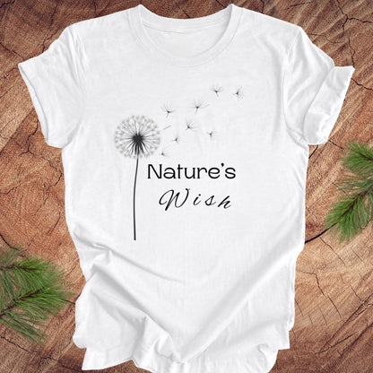 White t-shirt with 'Nature's Wish' and dandelion design on a wooden surface