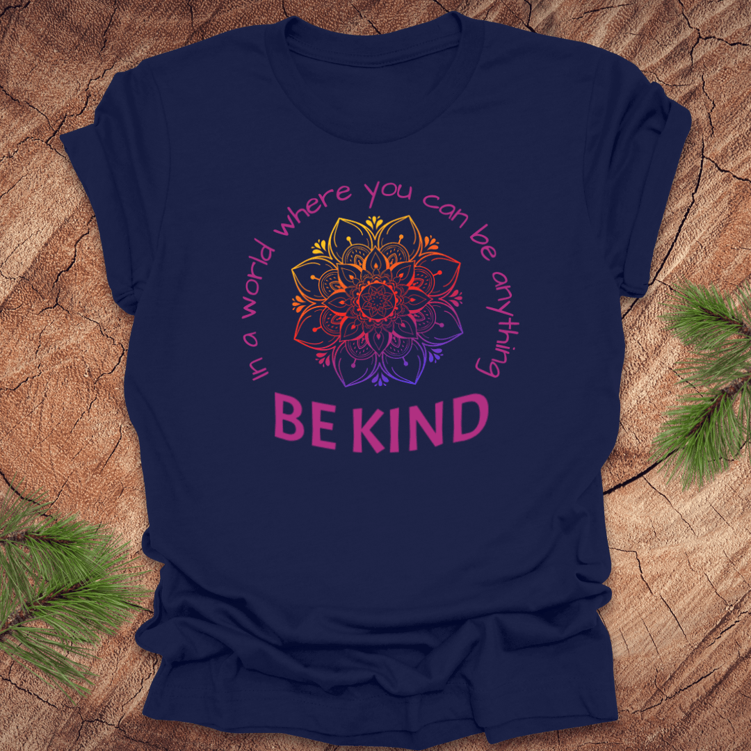 Navy blue t-shirt with a colorful mandala and 'Be Kind' text on a wooden surface.