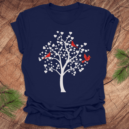 Navy blue t-shirt with a tree design featuring cardinals and white hearts on a wooden surface.