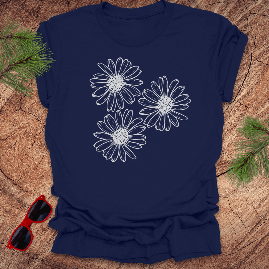 Navy blue t-shirt with 3 daisies prominently displayed. on a wooden surface with sunglasses and greenery.