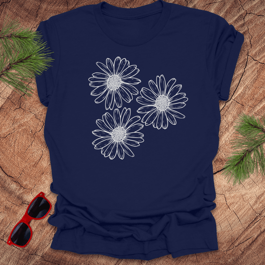 Navy blue t-shirt with 3 daisies prominently displayed. on a wooden surface with sunglasses and greenery.