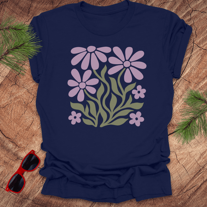 Navy blue t-shirt with floral design on a wooden surface with sunglasses and greenery.
