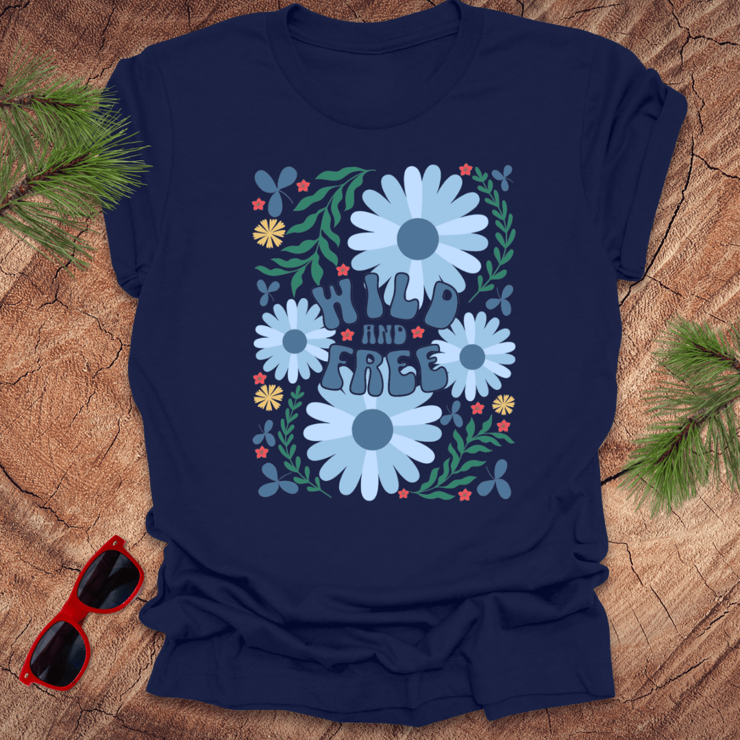 Navy blue t-shirt with floral design and 'Wild and Free' text on a wooden surface with sunglasses and greenery.
