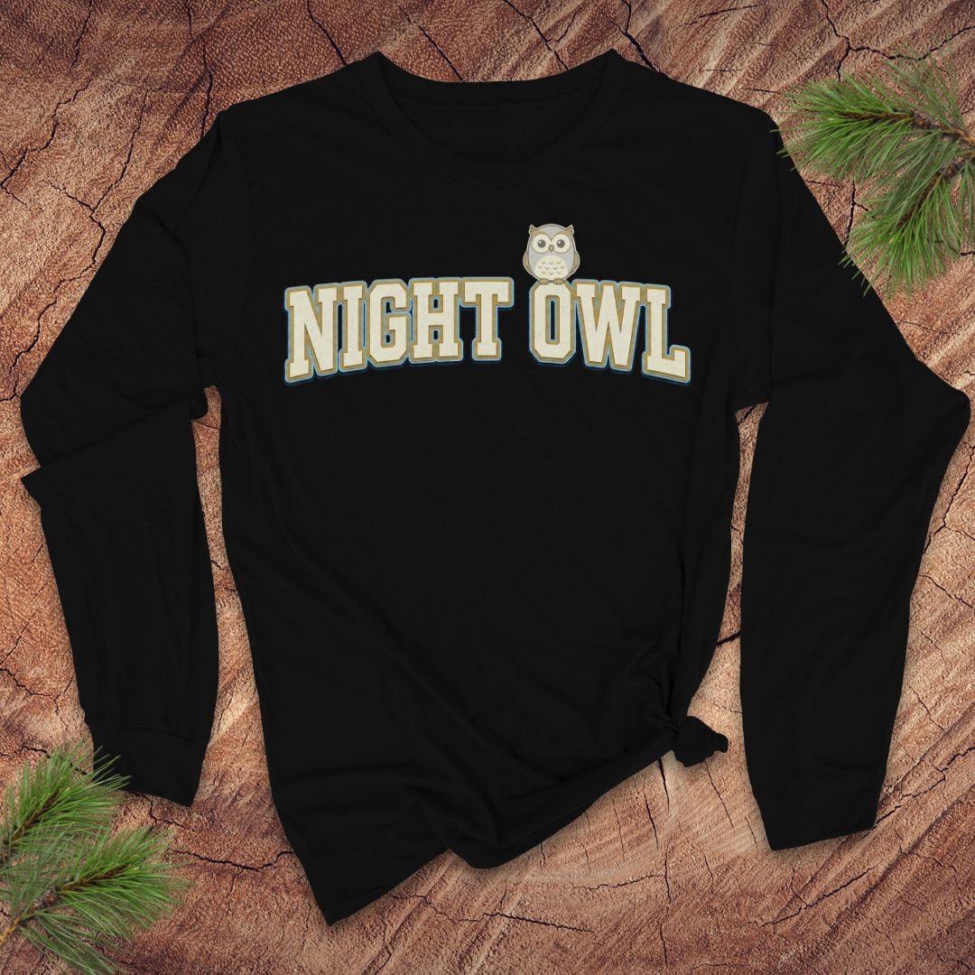 Black long sleeve tshirt with 'NIGHT OWL' text and owl graphic on a wooden surface.