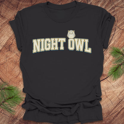 Dark gray t-shirt with 'NIGHT OWL' text and owl graphic on a wooden surface.