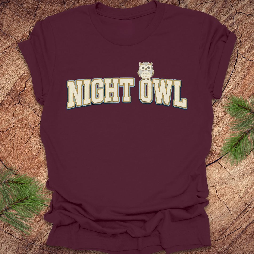 Maroon t-shirt with 'NIGHT OWL' text and owl graphic on a wooden surface.