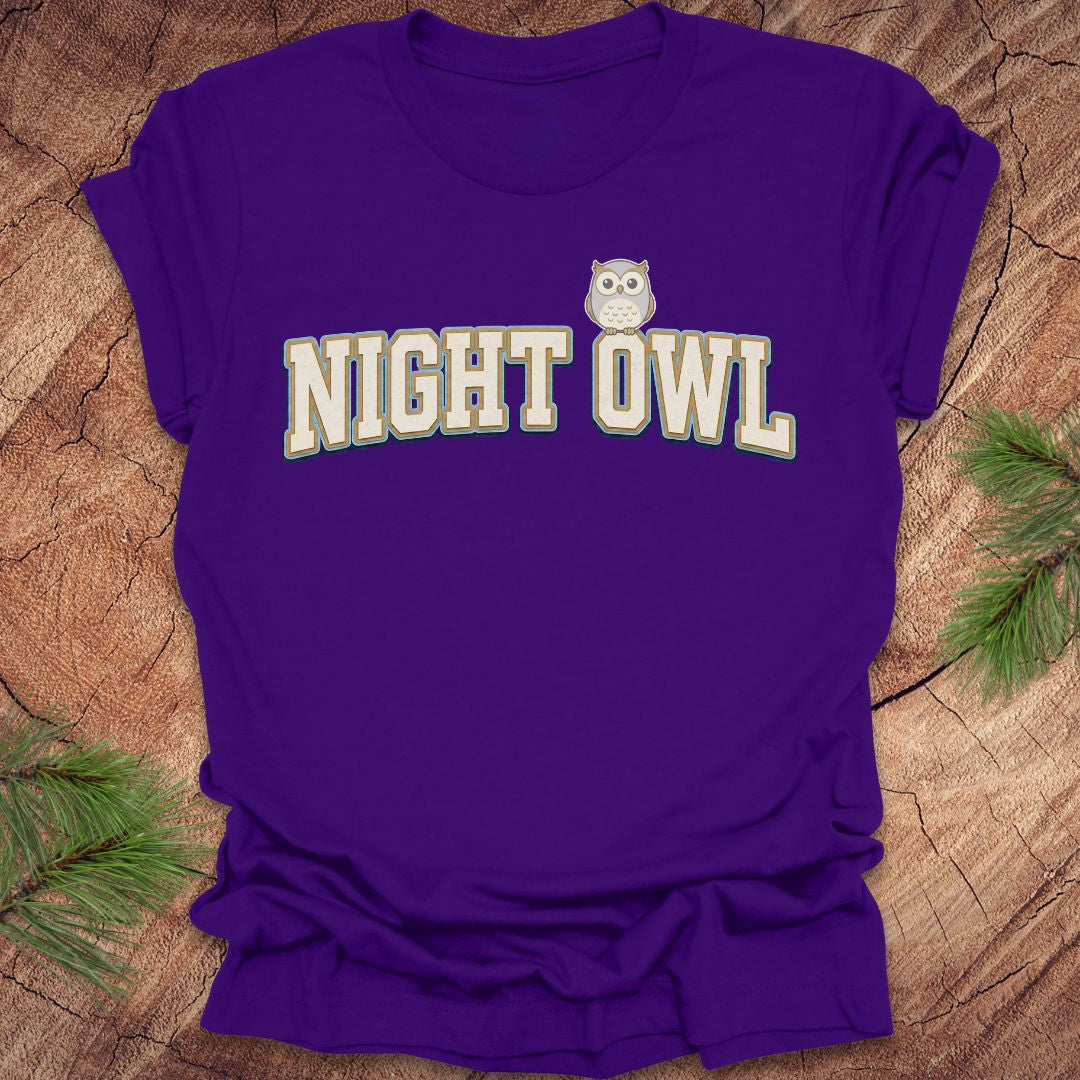 Purple t-shirt with 'NIGHT OWL' text and owl graphic on a wooden surface.