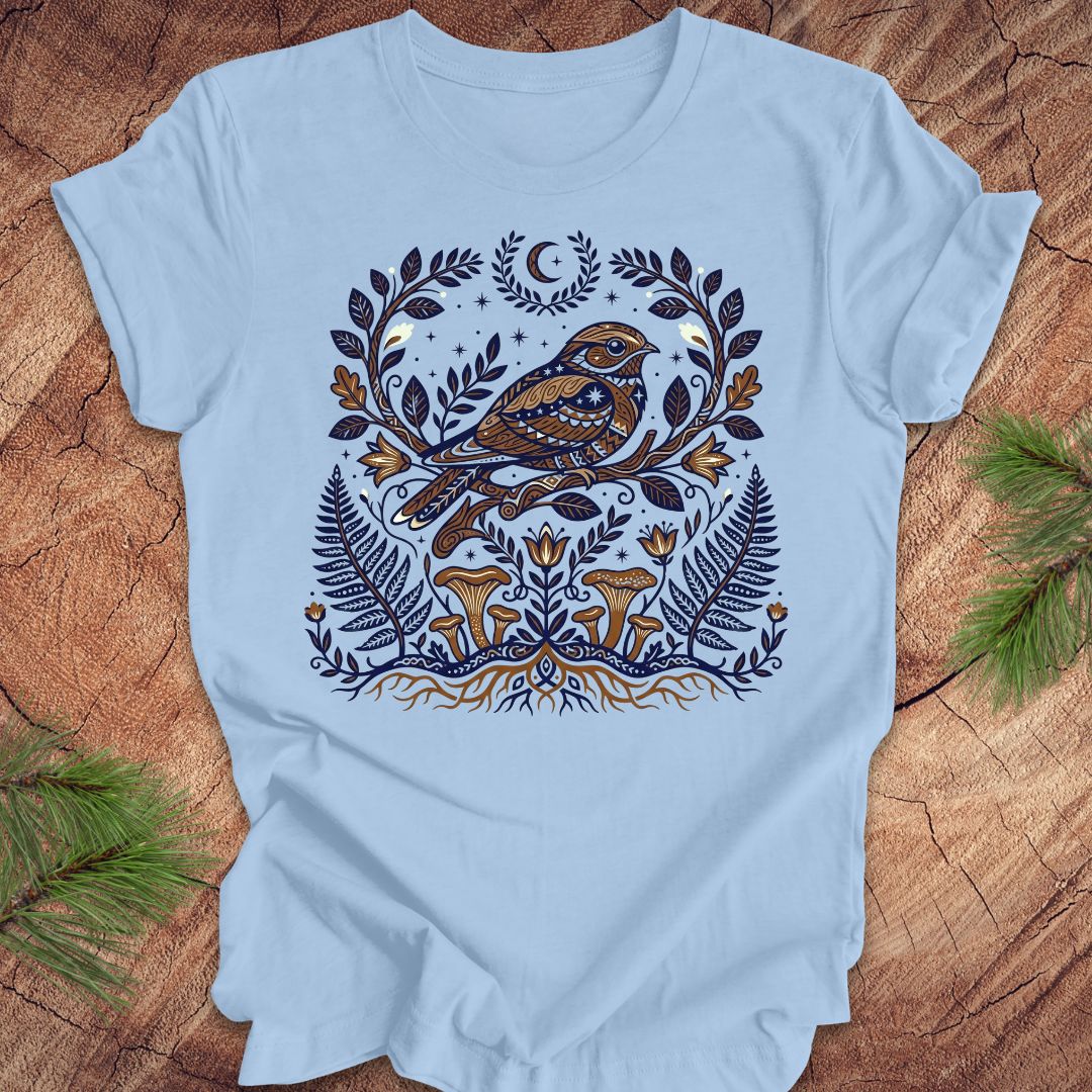 Light blue t-shirt with a whip-poor-will and nature-themed design on a wooden surface.