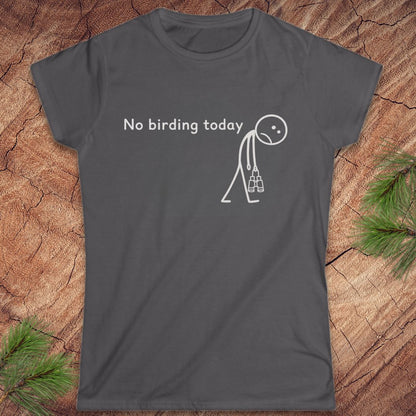 A dark gray short-sleeve t-shirt with a white graphic print that reads 'No birding today' next to a simple stick figure carrying birding bins. The shirt is displayed flat on a rustic wood background with pine needles in the corners.