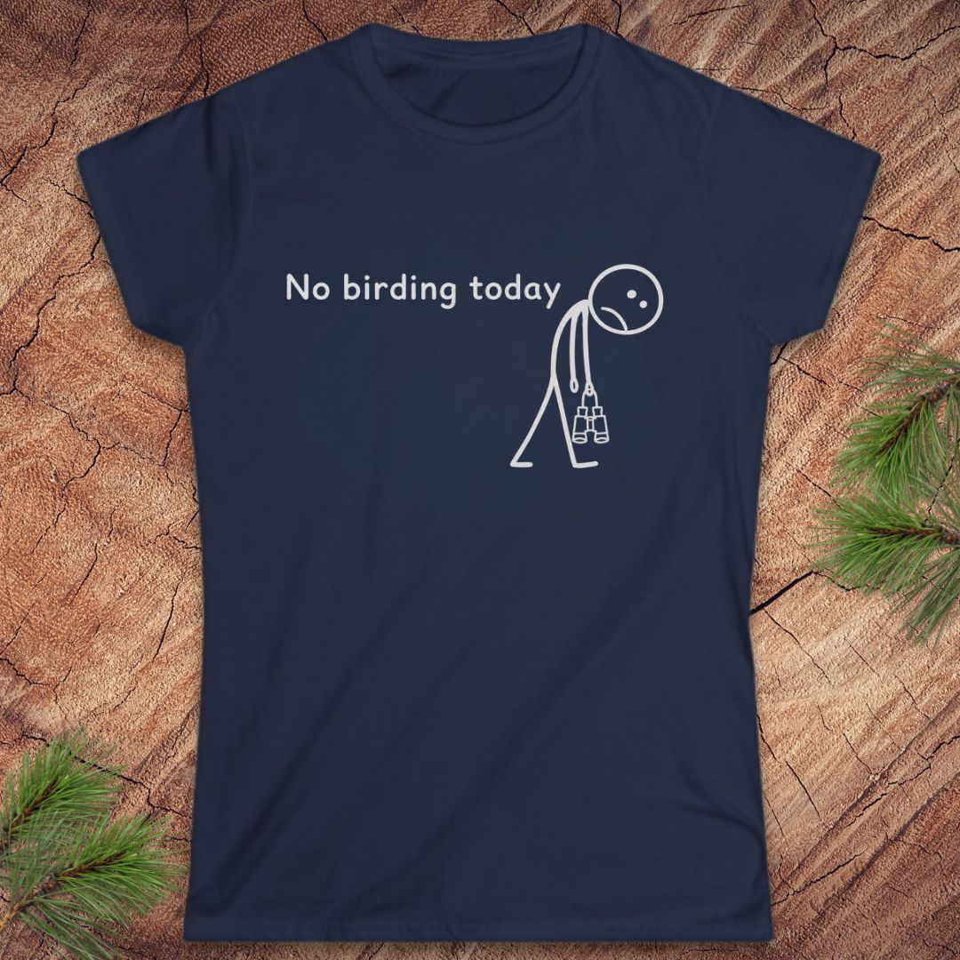 A navy blue short-sleeve t-shirt with a white graphic print that reads 'No birding today' next to a stick figure carrying a birdhouse. The t-shirt is displayed flat on a textured wood background with pine needles in the corners.
