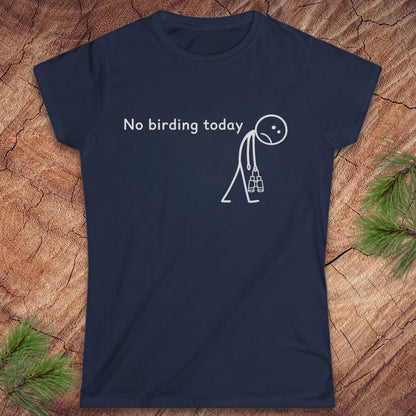 A navy blue short-sleeve t-shirt with a white graphic print that reads 'No birding today' next to a stick figure carrying a birdhouse. The t-shirt is displayed flat on a textured wood background with pine needles in the corners.