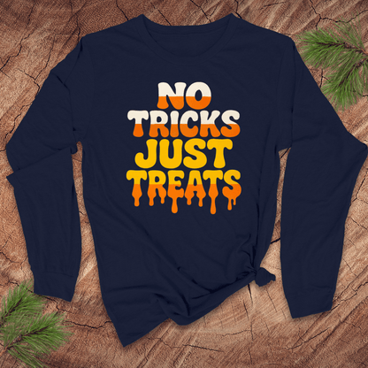Navy blue long-sleeve shirt with 'No Tricks Just Treats' text on a wooden surface with pine branches.