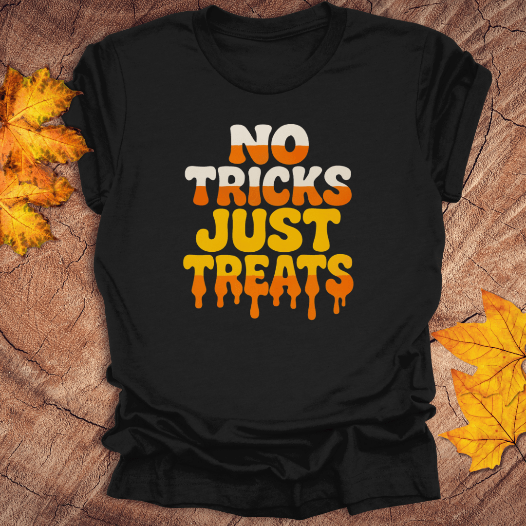 Black t-shirt with 'No Tricks Just Treats' text on a wooden surface with fall leaves.