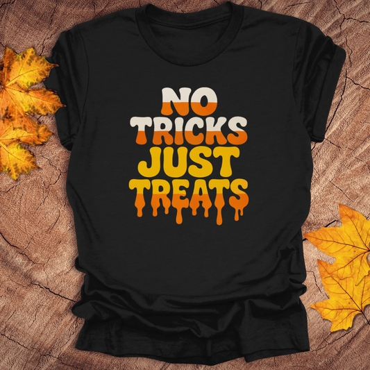 Black t-shirt with 'No Tricks Just Treats' text on a wooden surface with fall leaves.
