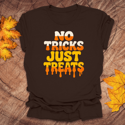 Brown t-shirt with 'No Tricks Just Treats' text on a textured surface with autumn leaves.