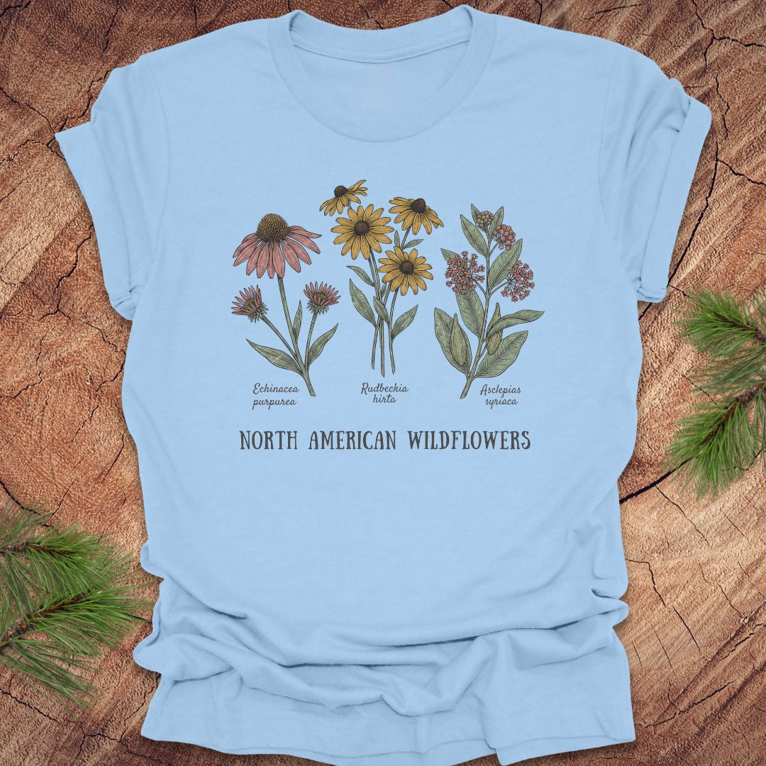 Baby blue t-shirt with North American wildflowers design on a wooden surface