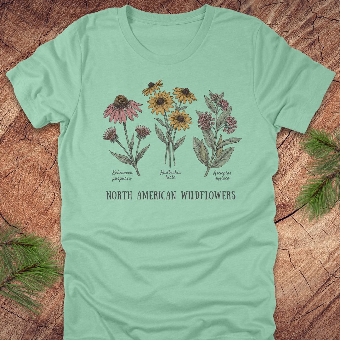 Mint green t-shirt with North American wildflowers design on a wooden surface