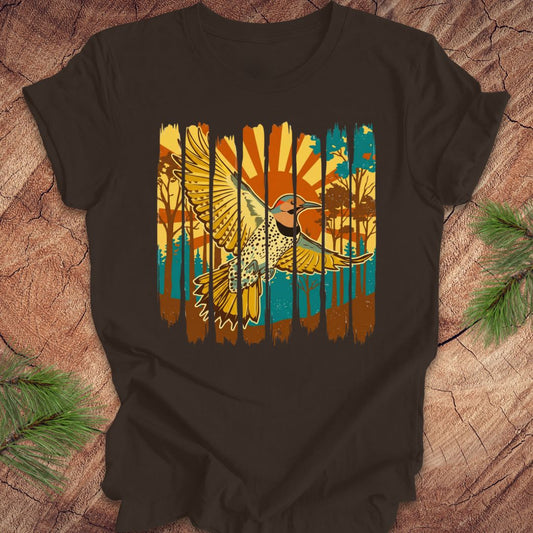 Brown t-shirt with a colorful graphic of a northern flicker and nature elements on a wooden surface.