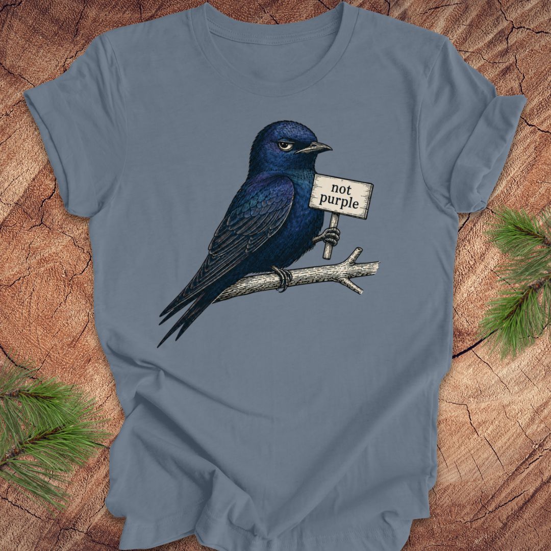 Blue t-shirt with a purple martin bird graphic and 'not purple' sign on a wooden surface