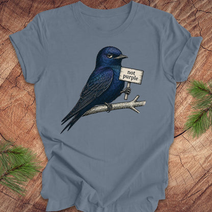 Blue t-shirt with a purple martin bird graphic and 'not purple' sign on a wooden surface