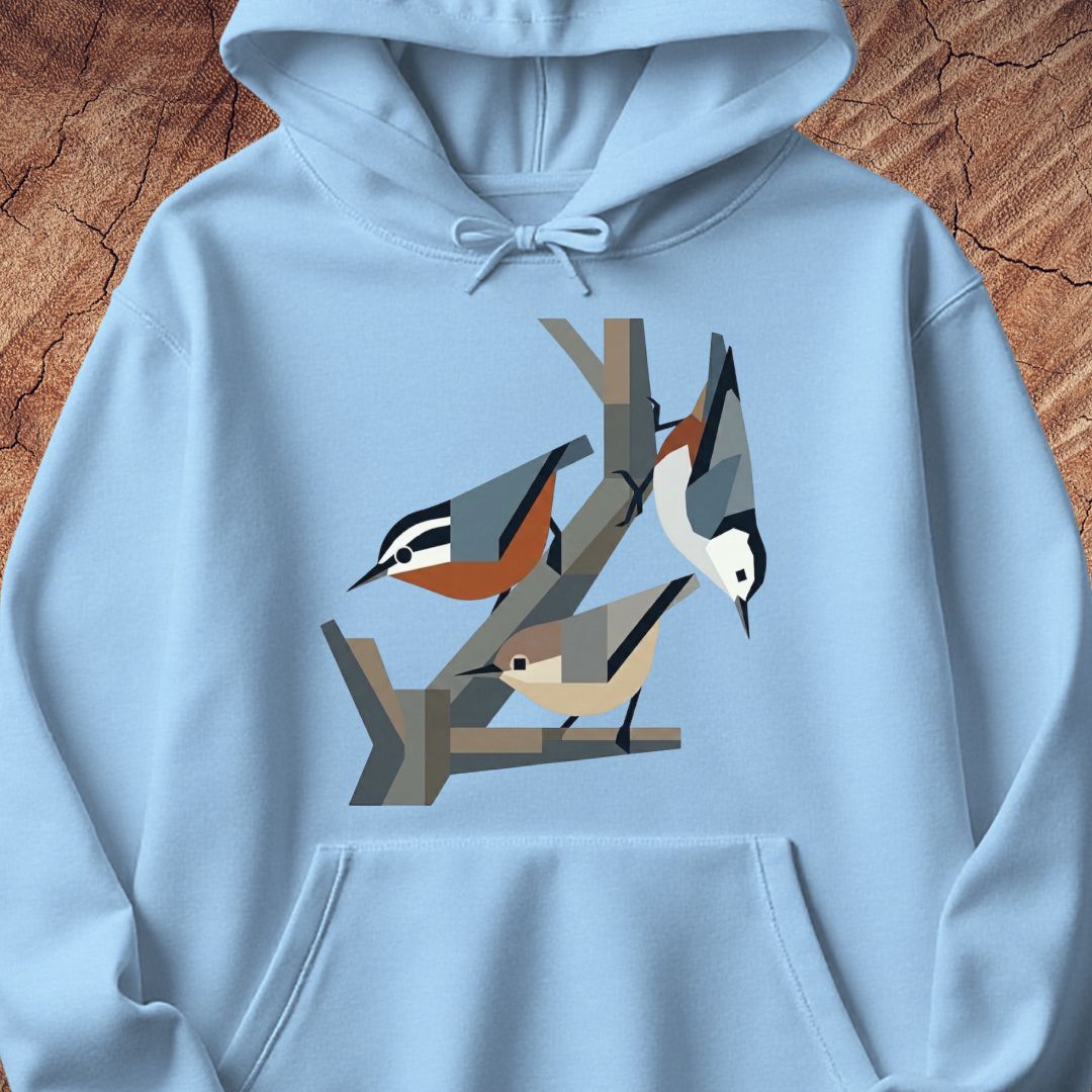 A light blue pullover hoodie featuring a stylized graphic print of three birds perched on branches, displayed flat against a textured brown wood background.