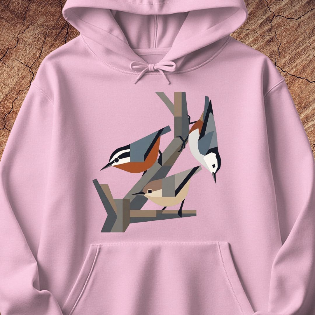 A light pink pullover hoodie featuring a stylized geometric graphic of three birds perched on branches on the chest, displayed flat against a rustic wood background.