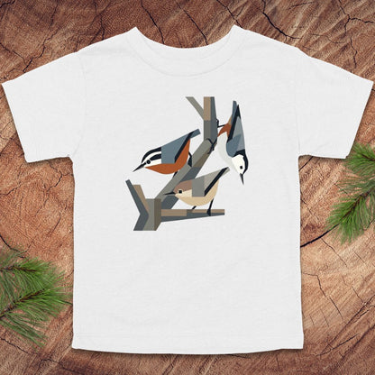 White toddler t-shirt with nuthatch bird design on a wooden surface