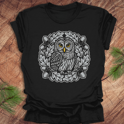 Black t-shirt with an owl in an oak tree design on a wooden surface