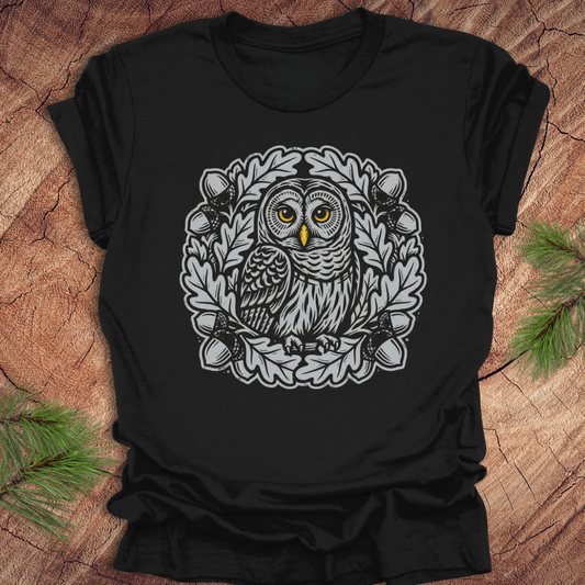 Black t-shirt with an owl in an oak tree design on a wooden surface