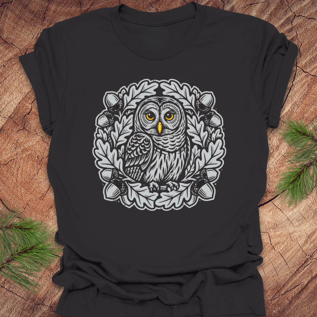 Dark gray t-shirt with an owl in an oak tree design on a wooden surface