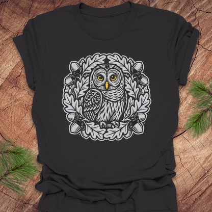 Dark gray t-shirt with an owl in an oak tree design on a wooden surface