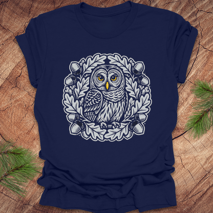 Navy blue t-shirt with an owl in an oak tree design on a wooden surface