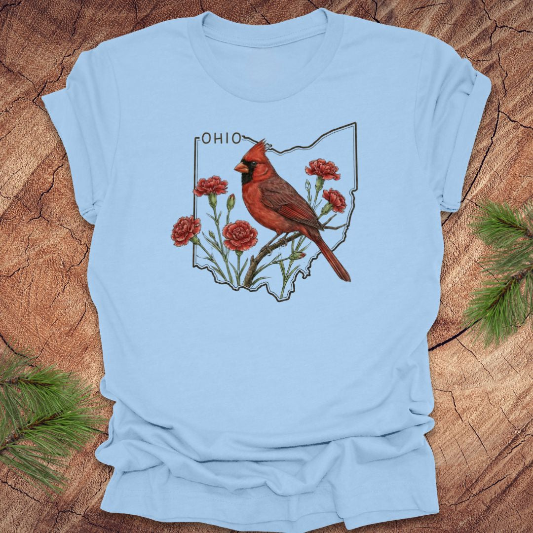 Baby blue t-shirt with a cardinal and floral design on an Ohio map, placed on a wooden surface.