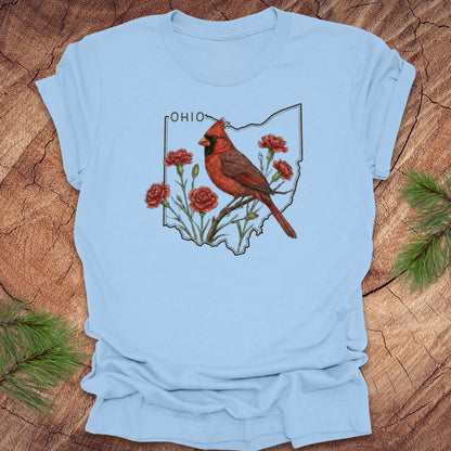 Baby blue t-shirt with a cardinal and floral design on an Ohio map, placed on a wooden surface.