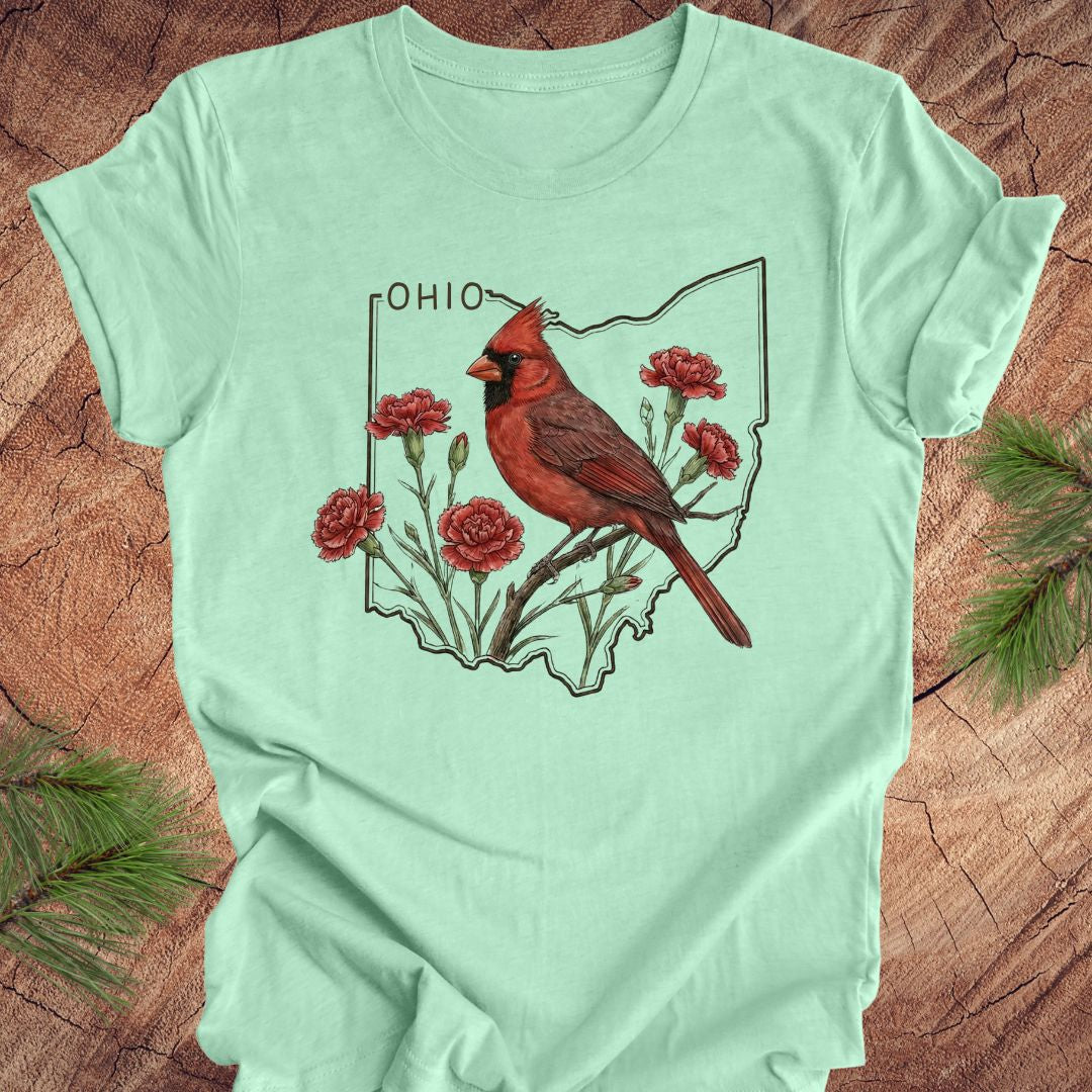 Light green t-shirt with a cardinal and floral design on an Ohio map, placed on a wooden surface.