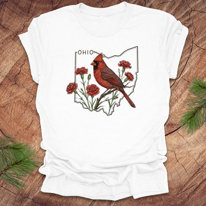 White t-shirt with a cardinal and floral design on an Ohio map, placed on a wooden surface.