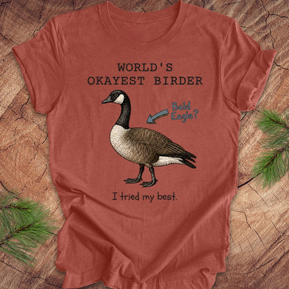 Red t-shirt with a goose graphic and text on a wooden surface