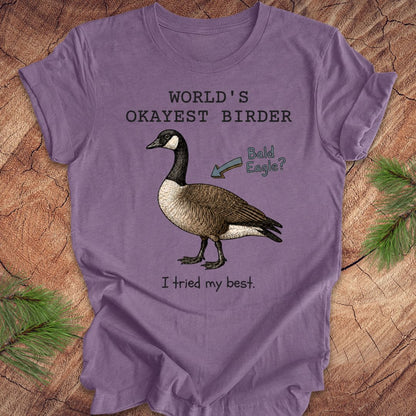 Purple t-shirt with a goose graphic and text on a wooden surface