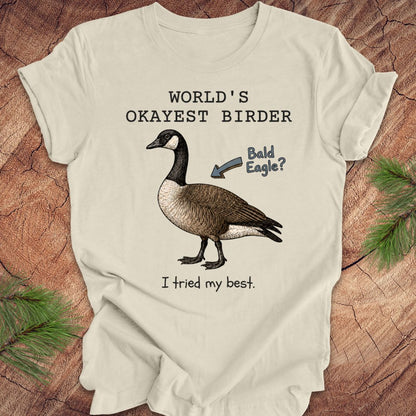 Beige t-shirt with a goose illustration and text on a wooden surface