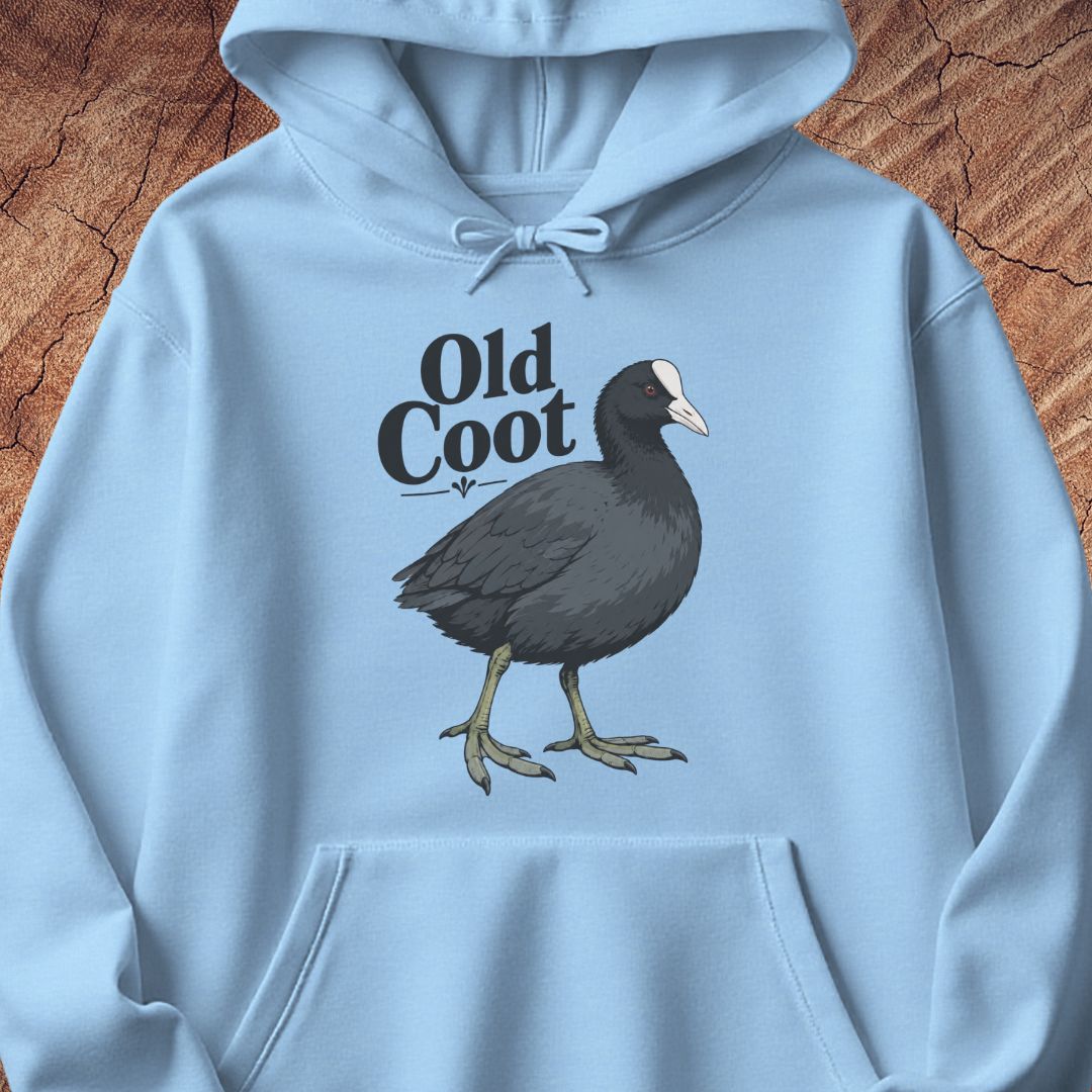 A light blue pullover hoodie featuring a graphic of a dark gray coot bird with a white beak and the text 'Old Coot' printed on the chest, displayed flat against a textured brown wood background.