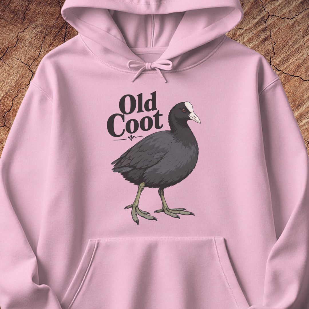 A light pink pullover hoodie laid flat on a textured wood background, featuring a graphic of a dark gray coot bird with a white beak and the text 'Old Coot' printed on the chest.