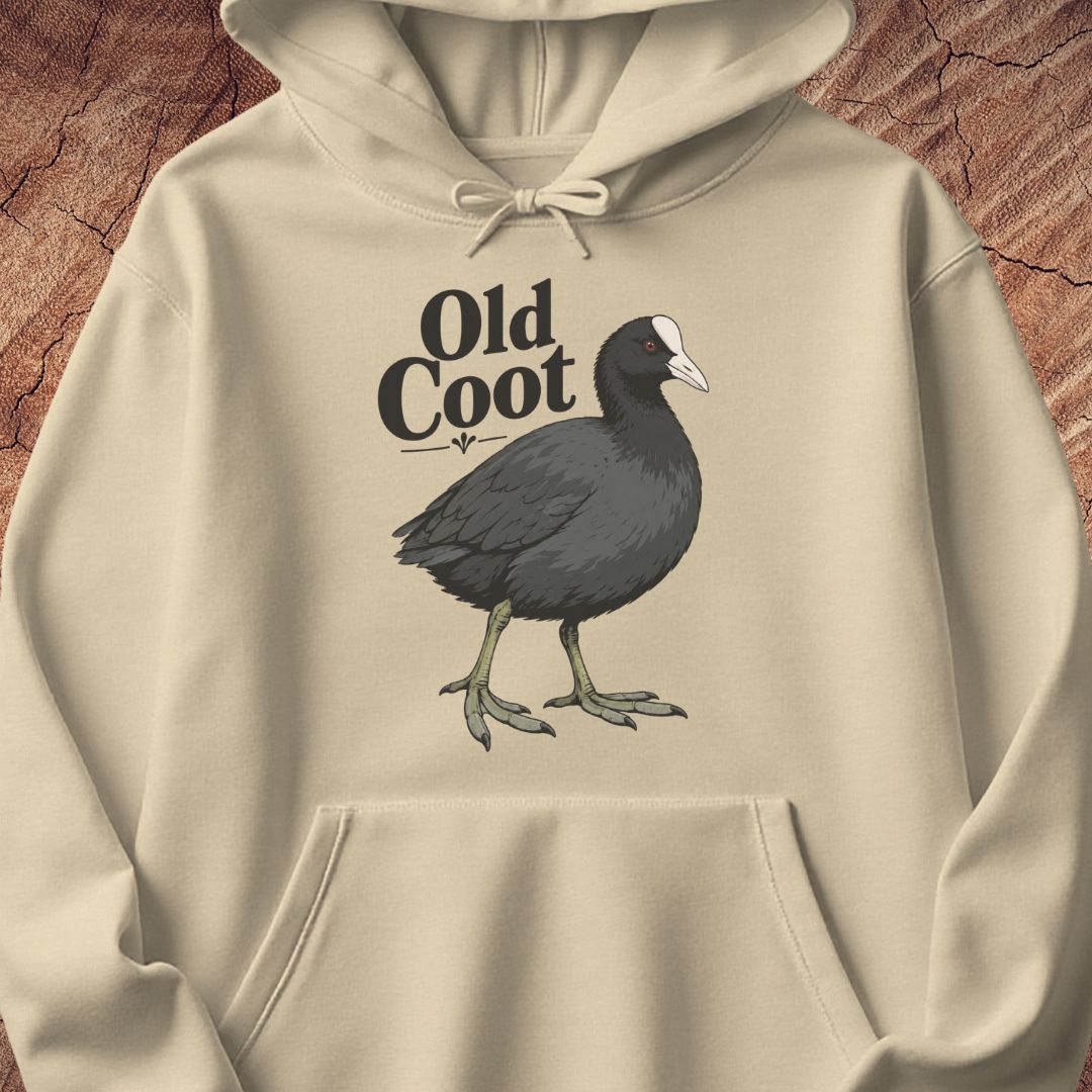A beige hoodie laid flat on a textured brown wood background, featuring a printed graphic of an old coot bird with the text 'Old Coot' above it.