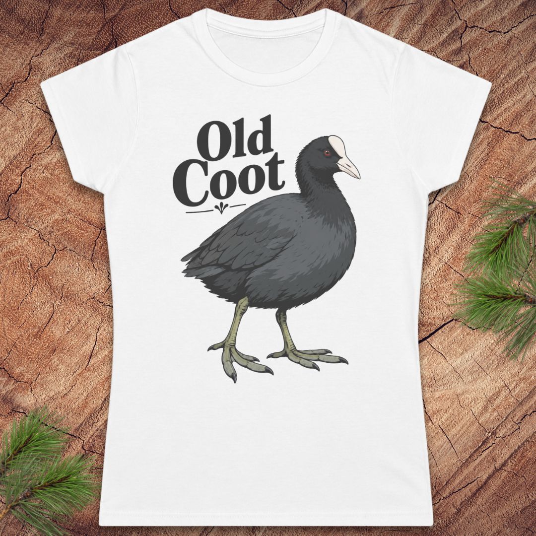A white short-sleeve crewneck t-shirt featuring a graphic of an 'Old Coot' bird and text, displayed flat on a rustic wood background with pine needles.