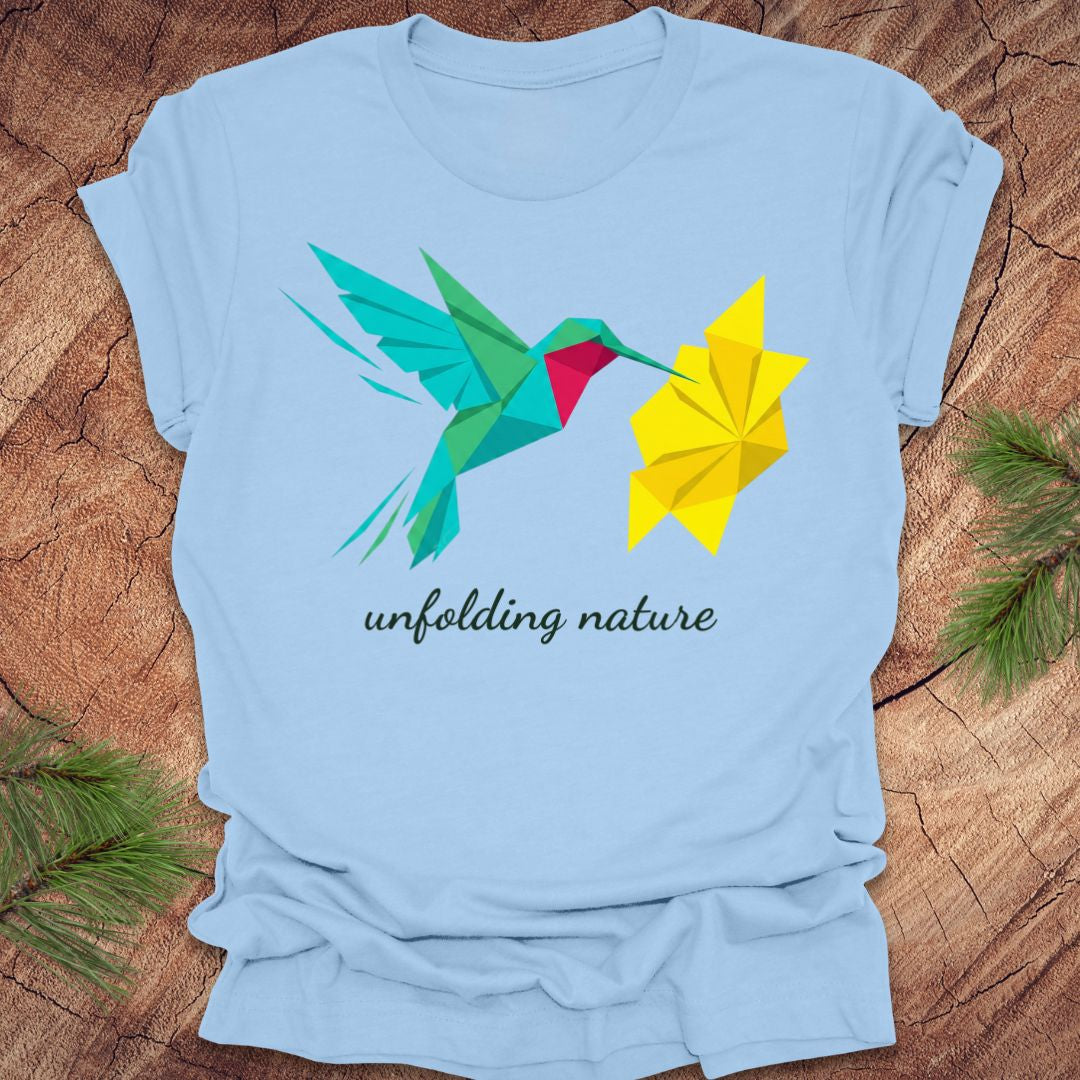Light blue t-shirt with a colorful hummingbird and flower design on a wooden surface.