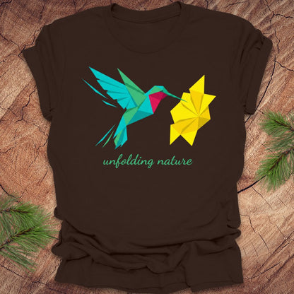 Brown t-shirt with a colorful design of a hummingbird and yellow flower on a wooden surface.