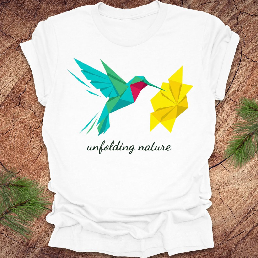 White t-shirt with a colorful hummingbird and leaf design on a wooden surface.