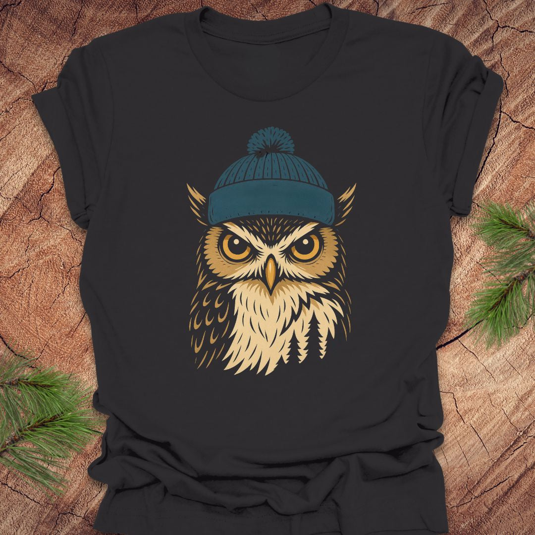 Black t-shirt with an owl wearing a blue beanie on a wooden surface.