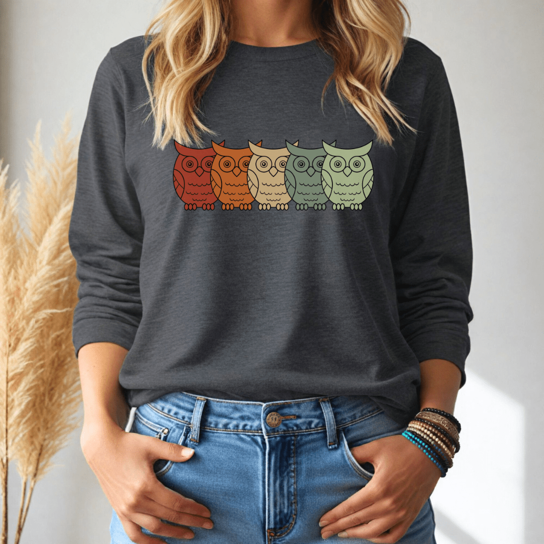 Person wearing a dark gray long sleeve tshirt with colorful owl design, standing against a neutral background.