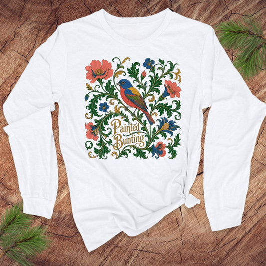 White long-sleeve shirt with a colorful bird and floral design on a wooden surface