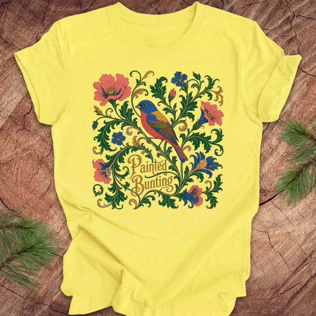 Yellow t-shirt with a painted bunting bird and floral design on a wood background.
